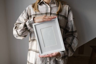 White frame for text in the hands of a girl close-up. Space for inscriptions and advertisements. Stylish piece of furniture