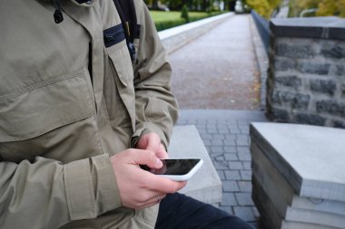 Bir adam elinde modern bir akıllı telefon tutuyor, mesaj gönderiyor ya da cep telefonunda bir uygulama kullanıyor. İş konsepti. Akıllı telefon, yakın plan. Telefon ekranına odaklan.