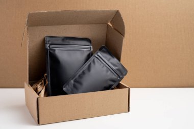 Arka planda çay, kahve, atıştırmalık ve kozmetik ürünleri için siyah paketler var. Ürünler için markalaşma ve paketleme modeli. Toparlanıyoruz. Satılık ürünler. Boş, model.