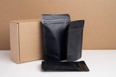 Arka planda çay, kahve, atıştırmalık ve kozmetik ürünleri için siyah paketler var. Ürünler için markalaşma ve paketleme modeli. Toparlanıyoruz. Satılık ürünler. Boş, model.