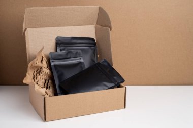 Arka planda çay, kahve, atıştırmalık ve kozmetik ürünleri için siyah paketler var. Ürünler için markalaşma ve paketleme modeli. Toparlanıyoruz. Satılık ürünler. Boş, model.