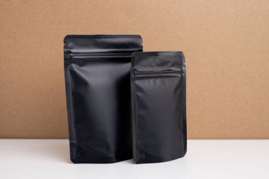 Arka planda çay, kahve, atıştırmalık ve kozmetik ürünleri için siyah paketler var. Ürünler için markalaşma ve paketleme modeli. Toparlanıyoruz. Satılık ürünler. Boş, model.
