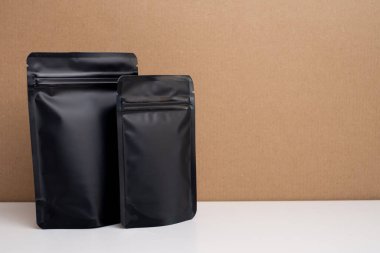 Arka planda çay, kahve, atıştırmalık ve kozmetik ürünleri için siyah paketler var. Ürünler için markalaşma ve paketleme modeli. Toparlanıyoruz. Satılık ürünler. Boş, model.
