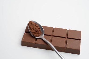 Kakao tozlu kaşık ve masanın üstünde lezzetli çikolata, üst manzara. Süt, siyah çikolata.