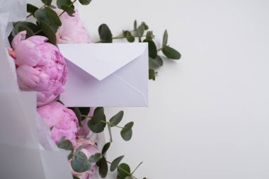 Kağıt, şakayık ve okaliptüs demetinde küçük bir zarf. Sevgililer gününde, doğum gününde, anneler gününde tebrik konsepti.