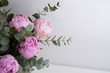 Güzel pembe şakayıklar ve okaliptüs dalları beyaz masa üzerinde metin, üst görünüm ve düz yatış tarzı için yer var.