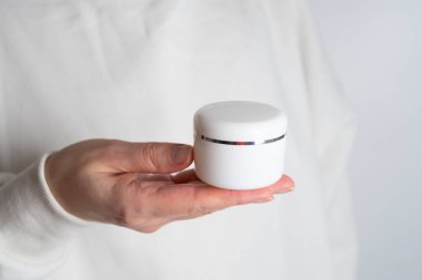 Bir kızın ellerinde bir kavanoz kaplıca kremi. Cilt bakımı. Eller için tıbbi ve dermatolojik kozmetik ürünleri. Bir kadının güzelliği ve sağlığı. Ceset için spa tedavisi. Doğal krem kaplamalı kap.