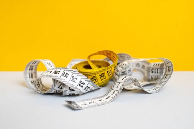 Arka planda çok renkli mezuralar var. Uzunluk ve hacim ölçme aracı. Dikiş üretimi veya insan vücut hacmi ölçümü için bant