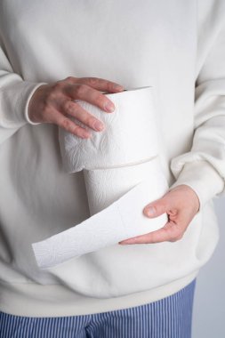 Kadının elleri yumuşak beyaz tuvalet kağıdı rulosunu tutuyor. Hijyen konsepti. Yakın plan.