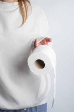 Kadının elleri yumuşak beyaz tuvalet kağıdı rulosunu tutuyor. Hijyen konsepti. Yakın plan.
