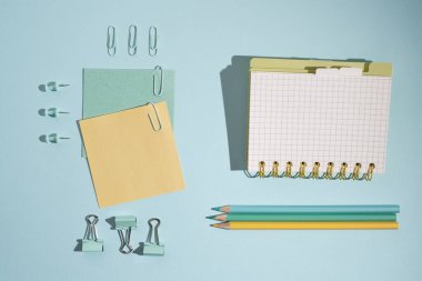 Not defteri, ataçlar, ataçlar ve yapışkan notlar, renkli arka planda kalemler. Ofis ya da okul malzemeleri.