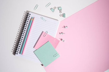 Not defteri, ataçlar, ataçlar ve yapışkan notlar, renkli arka planda kalemler. Ofis ya da okul malzemeleri.