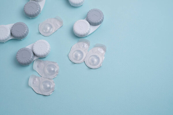 Contact lenses, case and bottle with solution and eye drops on white background. Eye health and care, vision, ophthalmology concept, close-up 