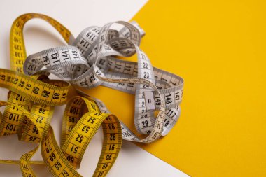 Arka planda çok renkli mezuralar var. Uzunluk ve hacim ölçme aracı. Dikiş üretimi veya insan vücut hacmi ölçümü için bant