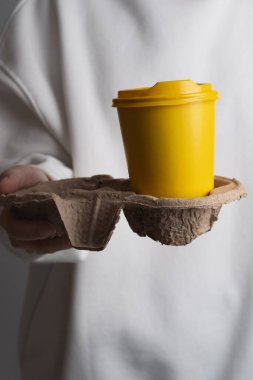 Kadın elinin içinde kahve olan kağıt bardak. Kahve içme zamanı. Paket kahve. Anın tadını çıkar, ara ver. Tek kullanımlık kağıt bardak yakın plan. Lezzetli sıcak içecek. Metin ve maket için boş boşluk