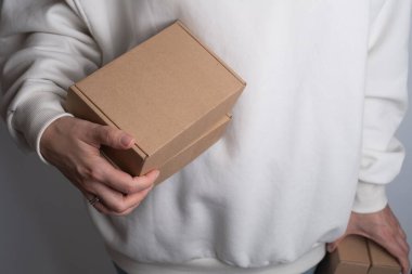 Elinde karton kutu tutan bir kadın. Yeni paketli bir kız. Posta servisi, teslimat. Kraft kağıdı. Hediye kutusu, hediye. Kutu yakın plan. Boş ambalaj, boş alan. Karton kutu.