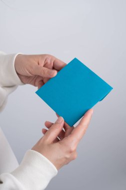 Kanepede otururken elinde tatil kartı tutan bir kız. Kağıt üzerinde davetiye için hoş bir mesaj. Metin için boş boşluk.