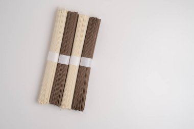 Bir paket kuru soba, çiğ karabuğday ve pirinç eriştesi, pişmemiş karabuğday makarnası, beyaz arka planda glütensiz soba spagettisi..