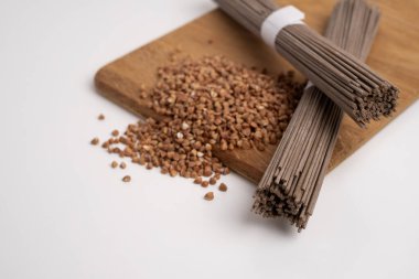 Bir paket kuru soba, çiğ karabuğday ve pirinç eriştesi, pişmemiş karabuğday makarnası, beyaz arka planda glütensiz soba spagettisi..