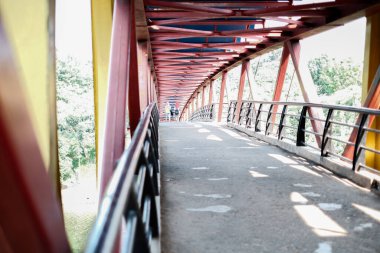 Kırmızı metal rayları ve mavi gökyüzü olan eski ahşap köprü.