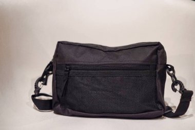 Beyaz arkaplanda siyah deri bir sırt çantası var.