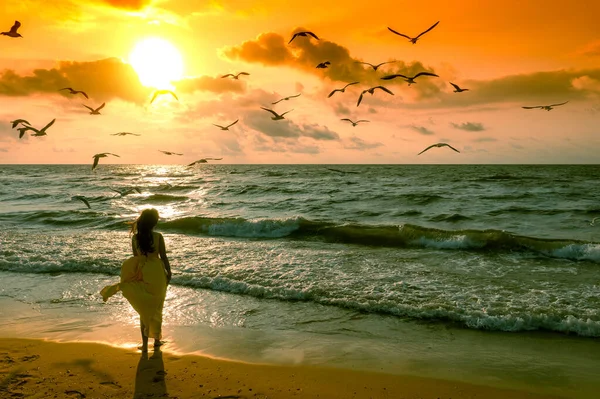 日出时的海景海滩上的女人一个穿着飘飘欲仙的衣服的年轻而快乐的女人沿着海滨散步 — 图库照片