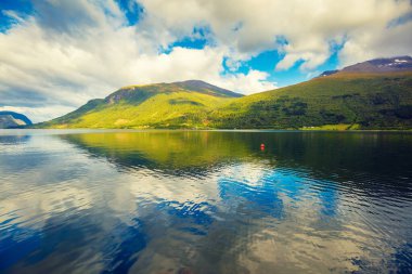 Mountain landscape with cloudy sky. Majestic Geiranger fjord.  Reflection in the water. Beautiful nature of Norway.