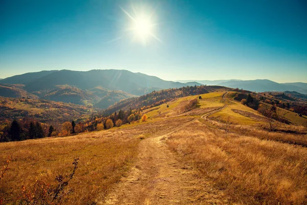 Mountain landscape on a sunny autumn day. View of the mountain slopes and dirt road. Beautiful nature landscape. Carpathian mountains. Ukraine