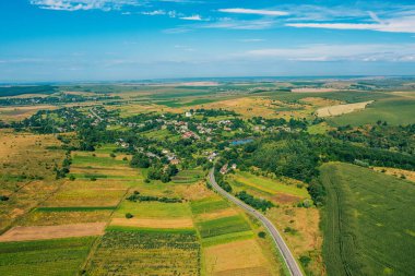 Air view of the countryside. Village, highway and cultivated fields on hills on a sunny summer day