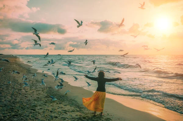 日出时带着美丽天空的海景 海滩上的女人夏天的时候年轻快乐的女人 手插在空中 穿着橙色的衣服在海滨散步 海鸥在海滩上飞翔 — 图库照片