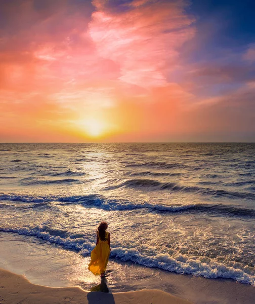日出时带着美丽天空的海景 海滩上的女人年轻的女人穿着一件黄色的飘逸的衣服在海滨 女孩看着神奇的日出 空中风景 垂直横幅 — 图库照片