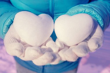 Kışın kadın ellerinde iki kalp şeklinde kartopu.