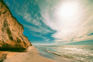 Kil gibi dik sahili olan deniz manzarası. Bulutlu bir günde deniz kıyısında