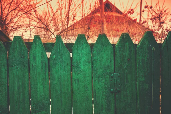 Wooden green fence in the village in early spring