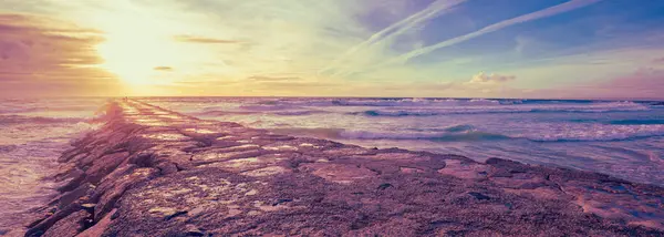 stock image Sunset over the Atlantic Ocean. A stone breakwater in the ocean. Horizontal banner