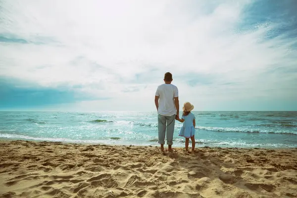 Bir baba küçük kızıyla birlikte akşamları kumsalda yürüyüp gün batımını seyreder. Mutlu çocukluklar ve Babalar Günü konsepti