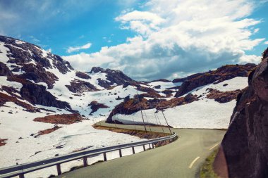 Yazın karla kaplı bir dağın arasında güzel bir dağ yolu. Norveç 'in güzel doğası