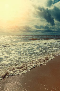 Denizin üzerinde gün batımı. Dalgalar kumlu kıyıya vuruyor. Doğa soyut arka plan. Dikey pankart