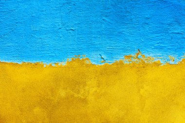 The concrete wall is half painted with blue and yellow  paint. Abstract grunge background. Bi-color concrete wall background. Ukrainian flag concept clipart