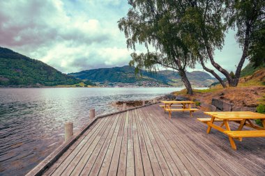 Bulutlu bir günde Sognefjord manzarası. Fiyort yakınlarında dinlenme yeri olan ahşap set. Kjornes Kampı, Sogndal, Norveç