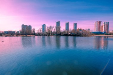 Kyiv in the morning. Left bank of the Dnieper River. Beautiful reflection of buildings in the lake clipart