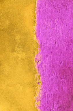 The concrete wall is half painted with yellow and pink color. Abstract grunge background. Bi-color concrete wall background. Vertical photo clipart