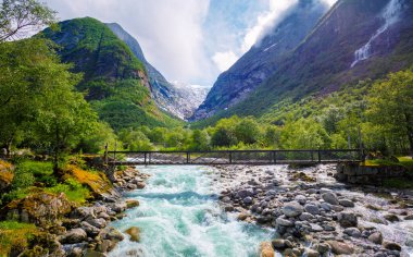 Güzel dağ nehri Dalelva (Stryn). Akıntılı çağlayan dağ deresi. Briksdal Köprüsü. Gelin Buzulu