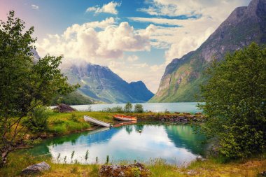 Amazing Norwegian landscape on a sunny day. Mountain valley with beautiful glacial lake Oldevatnet and two boats on the shore. clipart