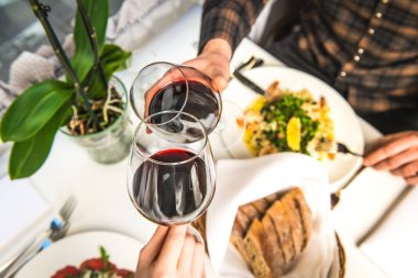 Bir restoranda iki misafir yıldönümünü kutluyorlar ve şarap kadehlerini tokuşturuyorlar..