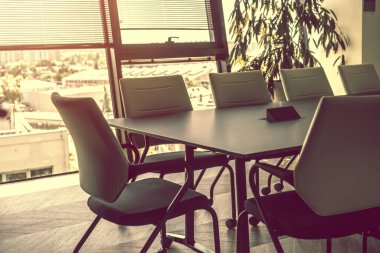 Konferans odasında toplantı bekliyorum. Toplantı odasında sandalyeli bir masa. Fotoğrafın sıcak renkleri. Ofis işi.