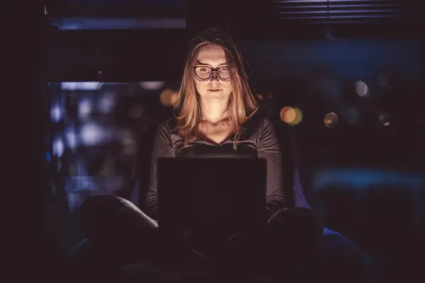 Nighttime internet browsing. Woman\'s face illuminated by a laptop screen.