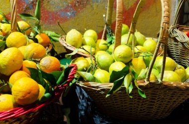 Sepetinde yeşil yapraklar olan büyük İtalyan limonları ve portakalları. İtalya 'nın Napoli caddelerinde sokak tezgahlarında birçok taze sebze ve meyve satılır. Yatay yönelim.