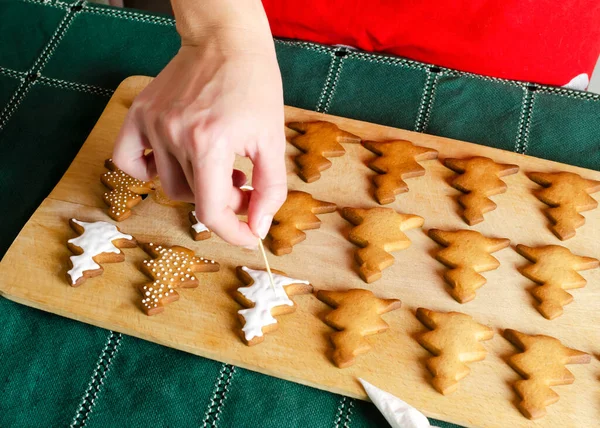 Baked cookies are decorated with white icing. The process of making homemade ginger and cinnamon Christmas cookies. The concept of home baking. Horizontal orientation. Selective focus