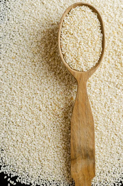 Wooden spoon with sesame seeds. Concept of healthy food. Vertical orientation